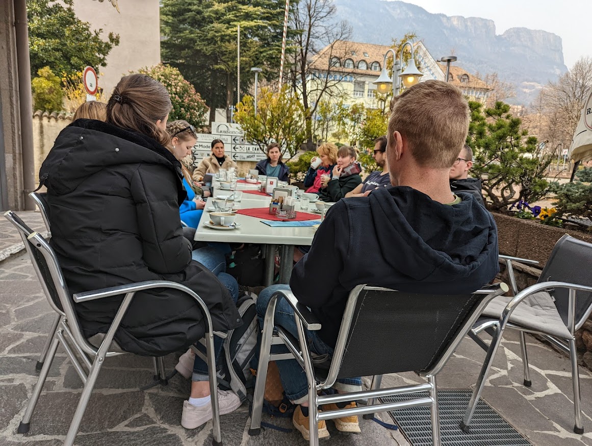 viele Studierende an einem Tisch mit Kaffeetassen, mit Blick auf Berge