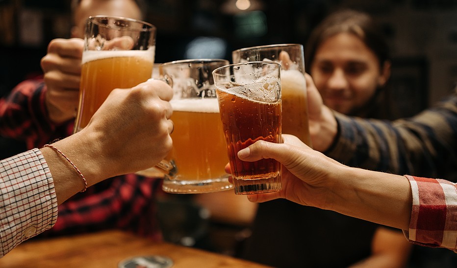 Personen stoßen Biergläser aneinander