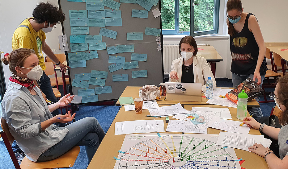 Studierende bei der Entscheidungsfindung zum nächsten Spielzug Gruppe Studierender am Tisch mit Brettspiel