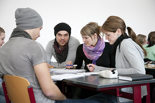 vier Studierende an einem Tisch mit Zettel und Stiften