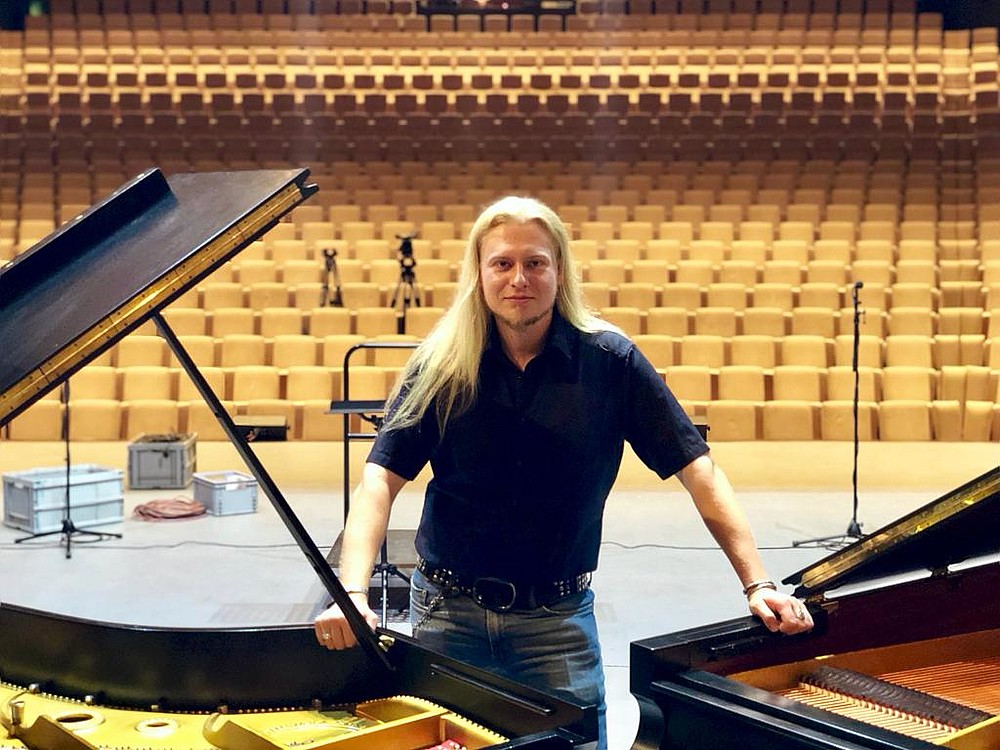 Bild von Toni Jährig zwischen zwei Flügeln im Konzertsaal
