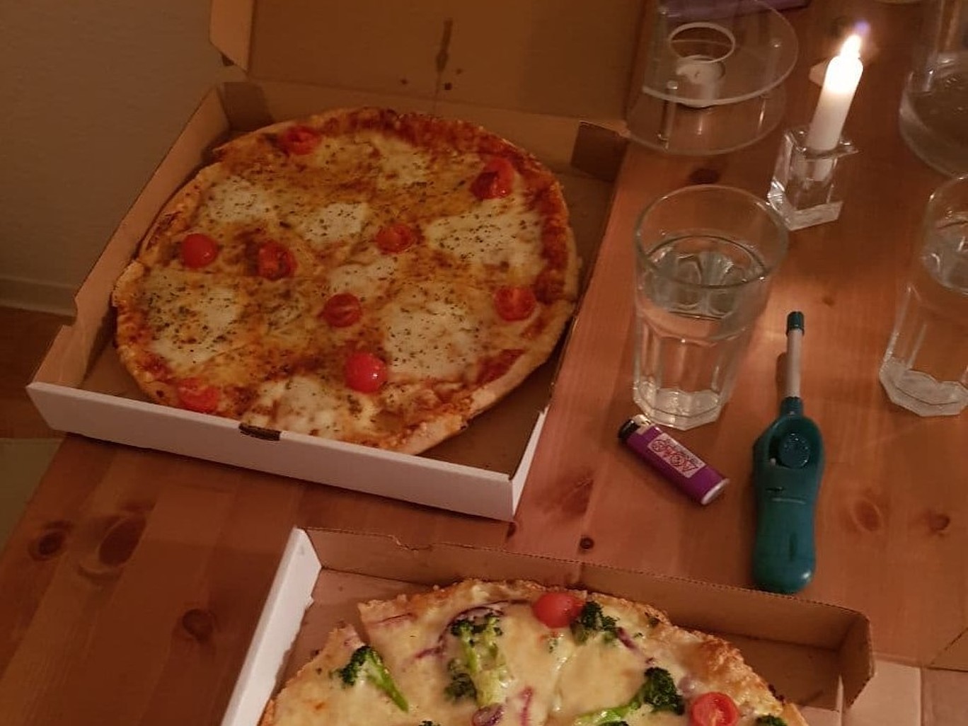 Tisch mit Pizzen und Gläsern und einer brennenden Kerze